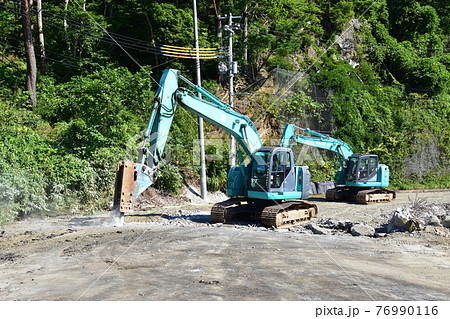 舗装道路をブレーカーで剥がす油圧ショベル 76990116