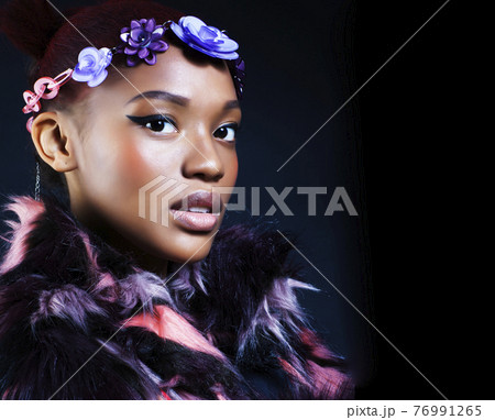 young pretty african american woman in spotted fur coat and flowers on head smiling on black background, fashion people concept young pretty african american woman in spotted fur coat and flowers on head smiling on black background, fashion people concept 76991265
