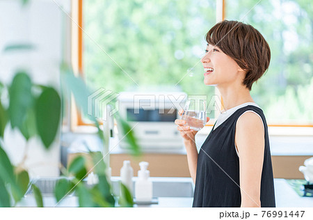 キッチンで水分補給する女性。 76991447