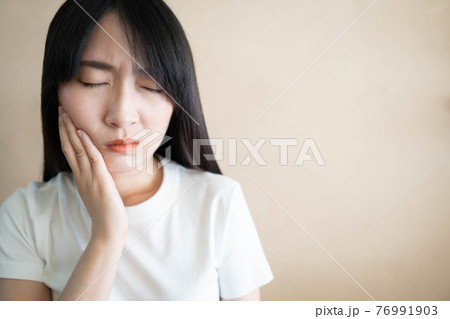 Young asian woman suffering from toothache or jaw pain. Cause of painful included tooth decay, inflammation, dental abscess, gum disease, sensitive teeth or trigeminal neuralgia. Health care concept. 76991903