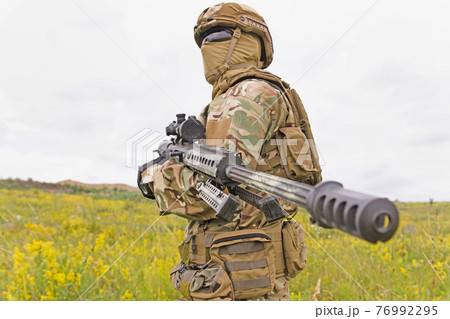 Special forces soldier standing in the field with rifle 76992295