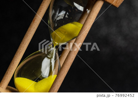 Close up'A yellow hourglass placed on a black background 76992452