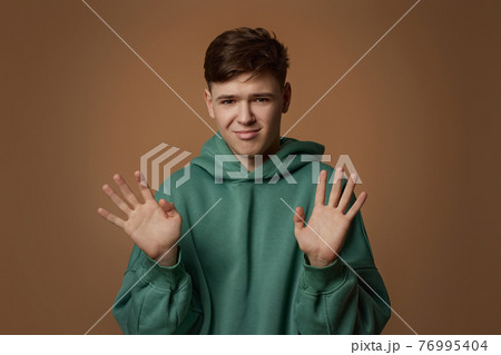 young scared man in sweatshirt on brown background. 76995404
