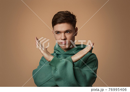young handsome guy in sweatshirt showing stop gesture young handsome guy in sweatshirt showing stop gesture 76995406