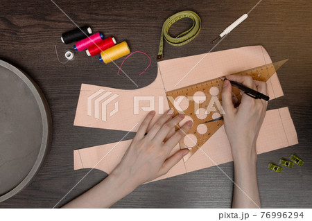 The seamstress makes a pattern. Sewing accessories and tools. Workplace of a seamstress. Creative hobby. The seamstress makes a pattern. Sewing accessories and tools. Workplace of a seamstress. Creative hobby. 76996294