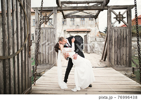 Beautiful romantic wedding couple of newlyweds hugging near old castle Beautiful romantic wedding couple of newlyweds hugging near old castle 76996438
