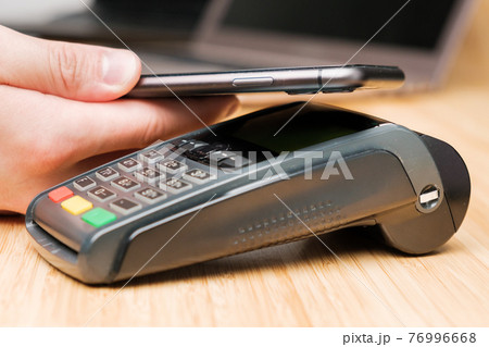 Man uses wireless terminal contactless payment with smartphone 76996668