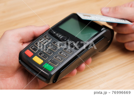 Close up man hand paying with contactless credit card with NFC technology using wireless payment terminal. Cashless payment during pandemic of coronavirus  76996669