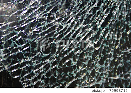 Texture of broken glass on dark background. Closeup 76998715