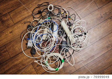 A tangled tangle of unnecessary wires lies on the floor A tangled tangle of unnecessary wires lies on the floor 76999049