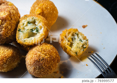 cheese balls with dill inside for a snack in a plate on a black background 76999577