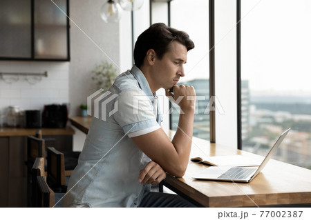Pensive male employee work on laptop thinking 77002387