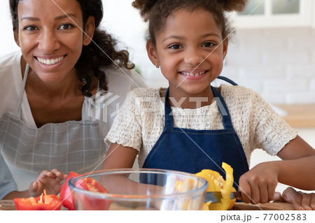 Portrait of happy mom and daughter wearing aprons 77002583
