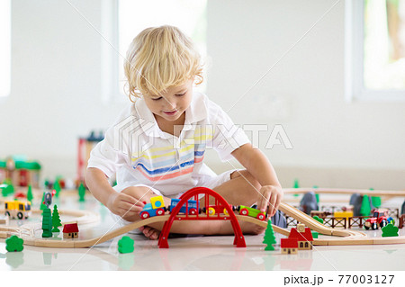 Kids play wooden railway. Child with toy train. 77003127