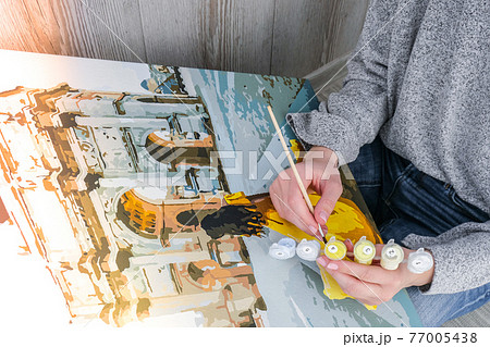 Female hands coloring canvas Picture by numbers girl Triumphal Arch Paris. Creative hobby. Painting for beginners. Leisure activity for stay home isolation, anti-stress idea. Meditation, relax concept 77005438
