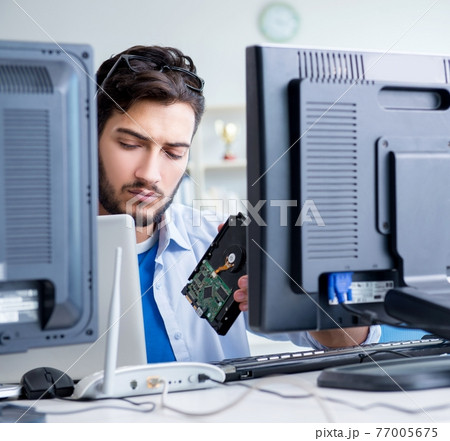IT technician looking at IT equipment IT technician looking at IT equipment 77005675