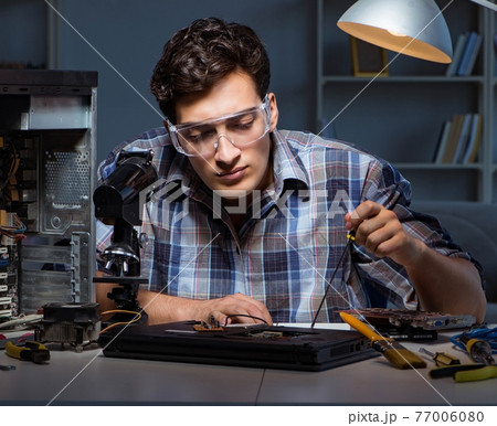 Young repair technician soldering electrical parts on motherboar Young repair technician soldering electrical parts on motherboar 77006080