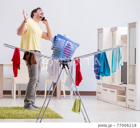 Handsome man husband doing laundering at home Handsome man husband doing laundering at home 77006218