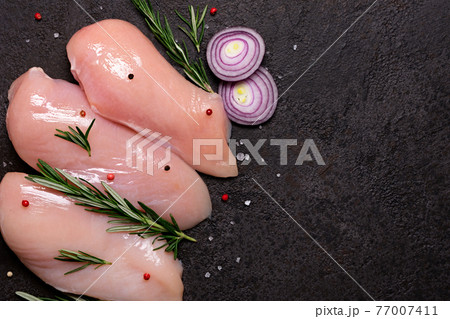 Raw chicken breast with spices and herbs on black stone background. Preparation for cooking 77007411