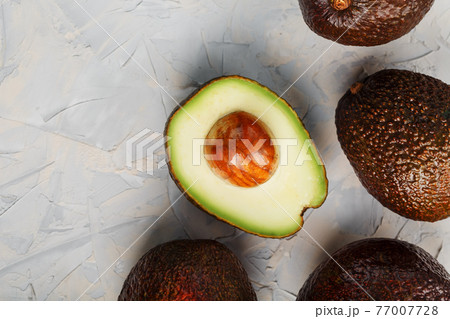 Sliced and whole organic Hass avocado on a gray background. Sliced and whole organic Hass avocado on a gray background. 77007728