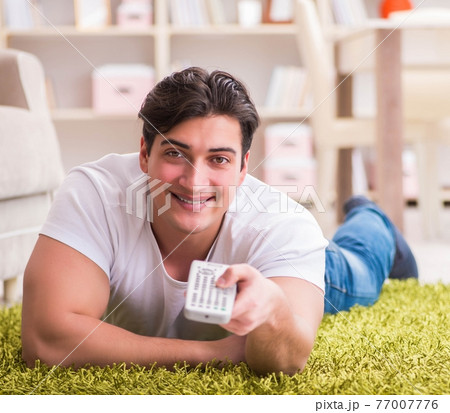 Man watching tv at home on floor 77007776