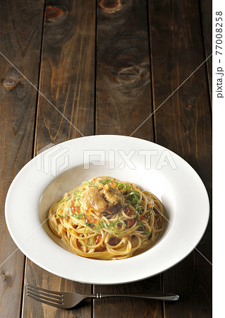 湯気が立つ、生ウニとイクラが乗っているウニクリームソースパスタとフォーク 77008258