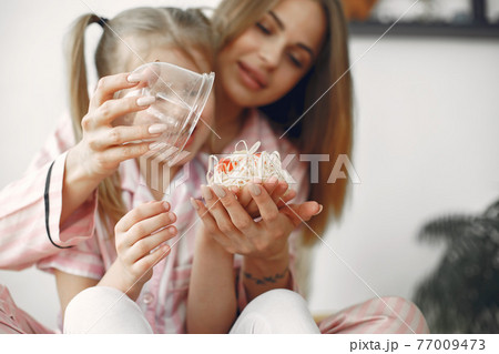 Mother and daughter opening gift on mother's day Mother and daughter opening gift on mother's day 77009473