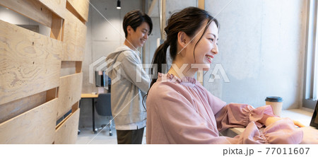 コワーキングスペースで立ってパソコン作業をする若い女性 バナーサイズ コワーキングスペースで立ってパソコン作業をする若い女性 バナーサイズ 77011607