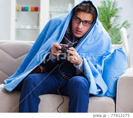 Employee suffering from flue playing computer game at home 77012275