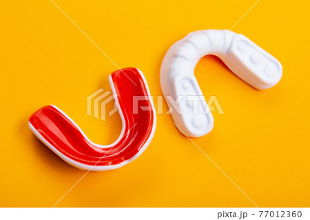 two boxing mouthguards, red and white, lie on a yellow background, concept, diagonal arrangement two boxing mouthguards, red and white, lie on a yellow background, concept, diagonal arrangement 77012360