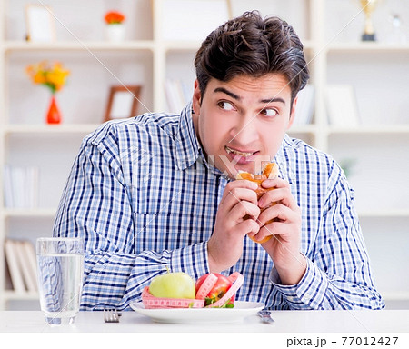 Man having dilemma between healthy food and bread in dieting con 77012427