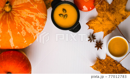 Autumn food. Frame of pumpkin puree soup, leaves. Top view. Autumn harvest, pumpkins, leaves on grey as abstract background. Thanksgiving day. Flat lay. Copy space 77012783