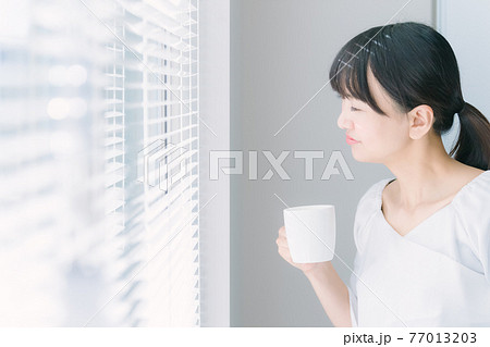 オフィスでマグカップを持つビジネスウーマン 77013203