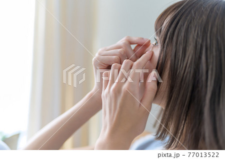 女性がコンタクトレンズを外す 77013522