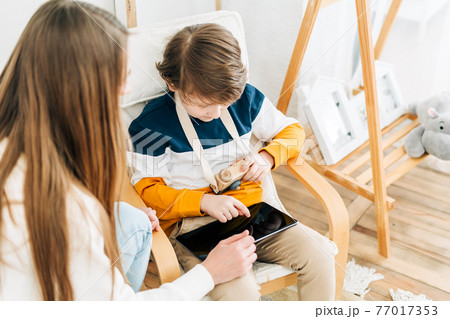 Mother with son in children's room, looking at tablet Mother with son in children's room, looking at tablet 77017353