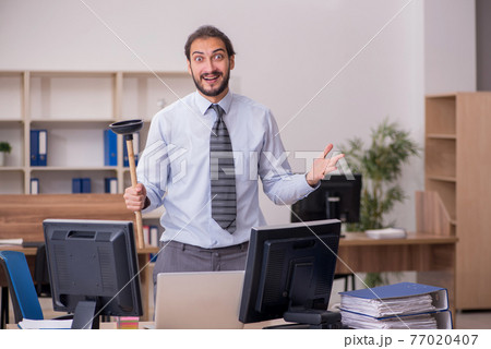 Young male employee holding plunger in funny concept 77020407