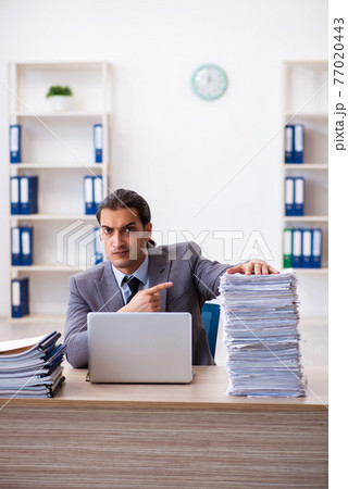 Young male employee unhappy with excessive work 77020443