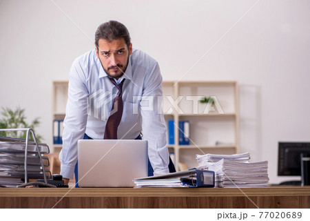 Young businessman employee unhappy with excessive work in the of Young businessman employee unhappy with excessive work in the of 77020689