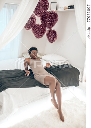 Good-looking pretty dark-skinned woman resting on the bed Good-looking pretty dark-skinned woman resting on the bed 77021007
