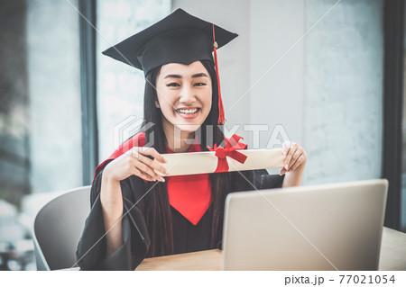 Cute asian smiling graduate holding her diploma and looking happy 77021054