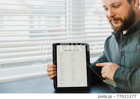Man showing visa application on tablet at office. Man showing visa application on tablet at office. 77021377