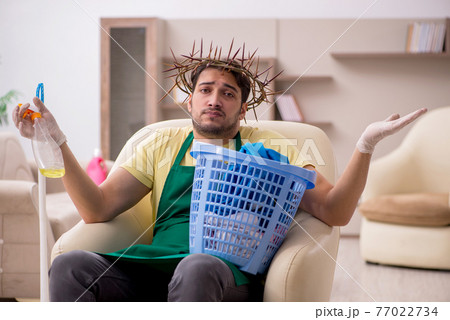 Young male contractor wearing prickly wreath on head cleaning th Young male contractor wearing prickly wreath on head cleaning th 77022734
