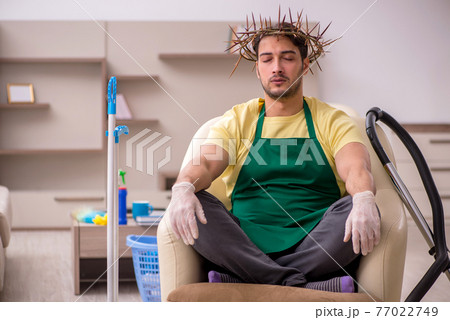 Young male contractor wearing prickly wreath on head cleaning th Young male contractor wearing prickly wreath on head cleaning th 77022749