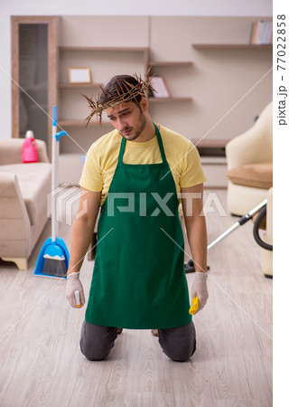 Young male contractor wearing prickly wreath on head cleaning th 77022858
