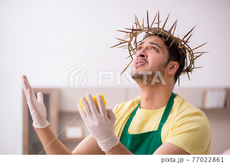 Young male contractor wearing prickly wreath on head cleaning th Young male contractor wearing prickly wreath on head cleaning th 77022861