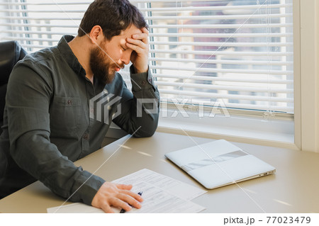 Tired thinking business director working with documents at office, closed laptop on desk. 77023479