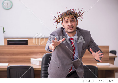 Young male employee wearing prickly wreath on head Young male employee wearing prickly wreath on head 77023891