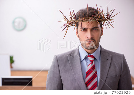 Young male employee wearing prickly wreath on head 77023929