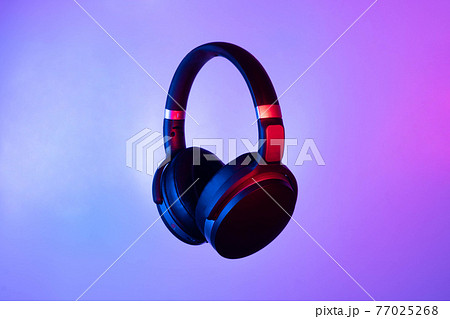 Black wireless bluetooth headphones on neon light background. Music concept. 77025268