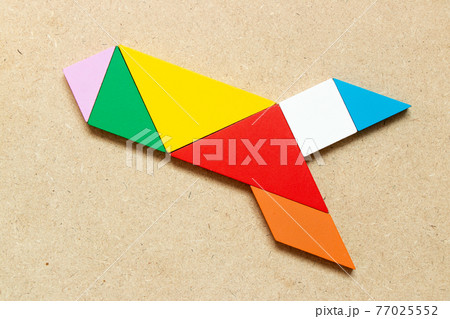 Color tangram puzzle in missile or rocket shape on wood background Color tangram puzzle in missile or rocket shape on wood background 77025552